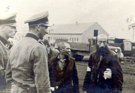 Two SS officers standing beside Jewish laborers.